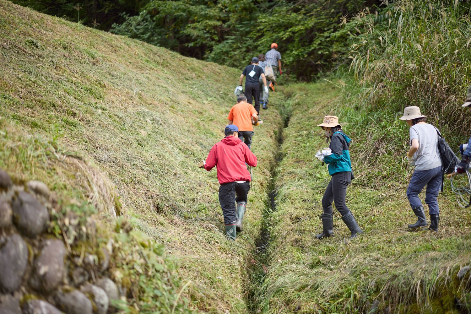 草地の溝に沿って歩く参加者